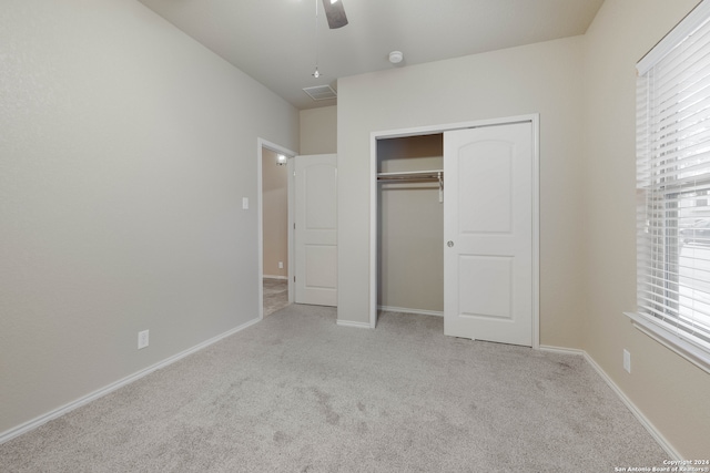 unfurnished bedroom featuring light carpet, multiple windows, ceiling fan, and a closet