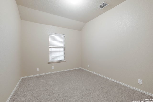 carpeted empty room with vaulted ceiling and a textured ceiling