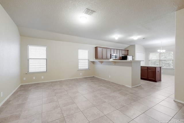 kitchen with refrigerator, kitchen peninsula, light tile patterned floors, a chandelier, and decorative light fixtures