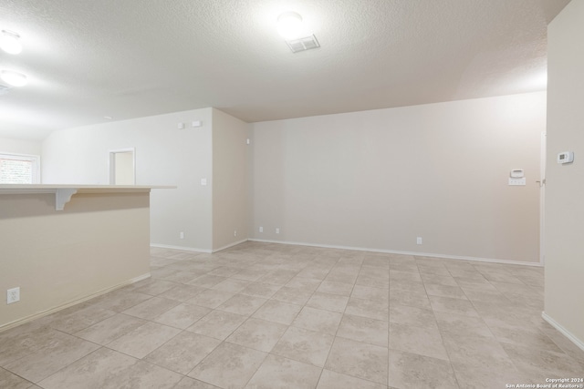 tiled empty room featuring a textured ceiling