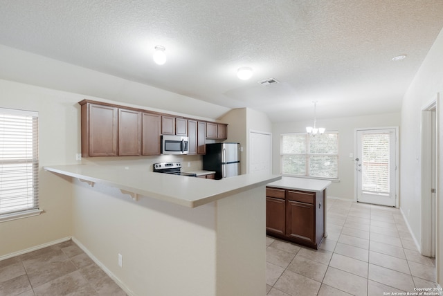 kitchen featuring pendant lighting, appliances with stainless steel finishes, lofted ceiling, and plenty of natural light