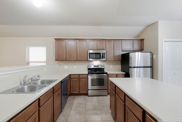 kitchen with sink, light tile patterned floors, vaulted ceiling, and stainless steel appliances