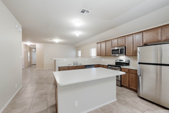 kitchen featuring stainless steel appliances, sink, light tile patterned floors, a kitchen island, and vaulted ceiling