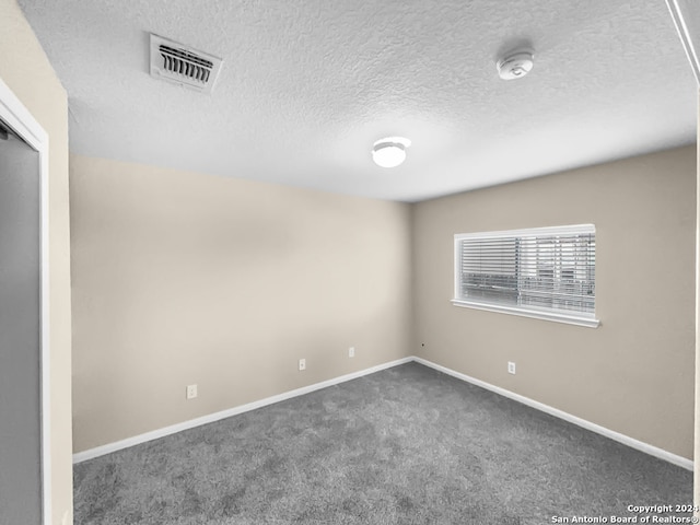 carpeted empty room featuring a textured ceiling