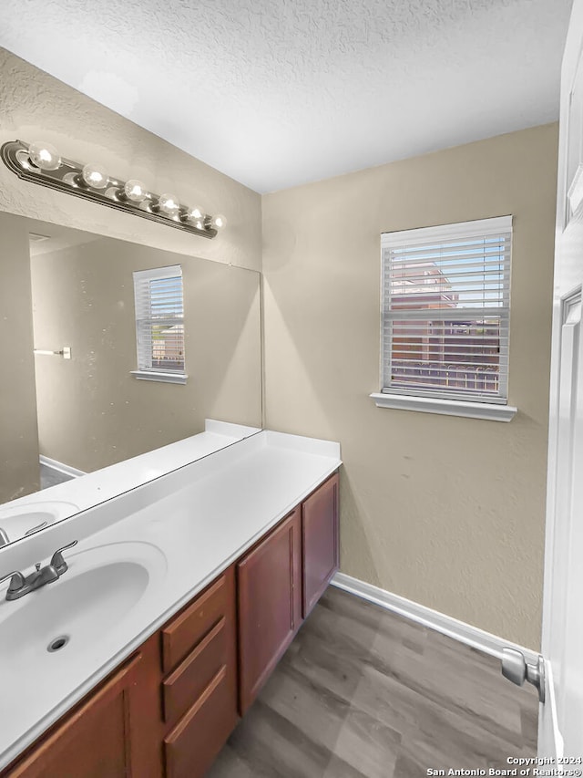 bathroom with a textured ceiling, vanity, hardwood / wood-style flooring, and a healthy amount of sunlight