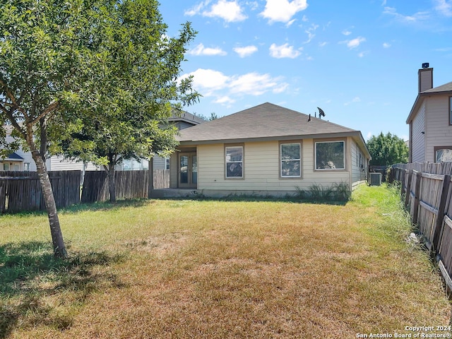 back of house with cooling unit and a yard