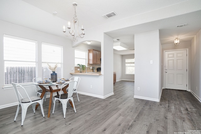 dining space with sink, light hardwood / wood-style floors, and a notable chandelier