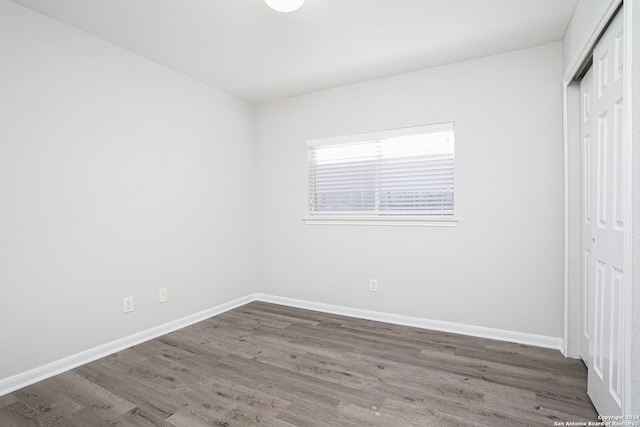 unfurnished bedroom with dark hardwood / wood-style flooring and a closet