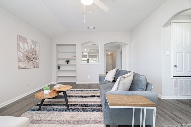 living room with lofted ceiling, built in features, ceiling fan, and dark wood-type flooring