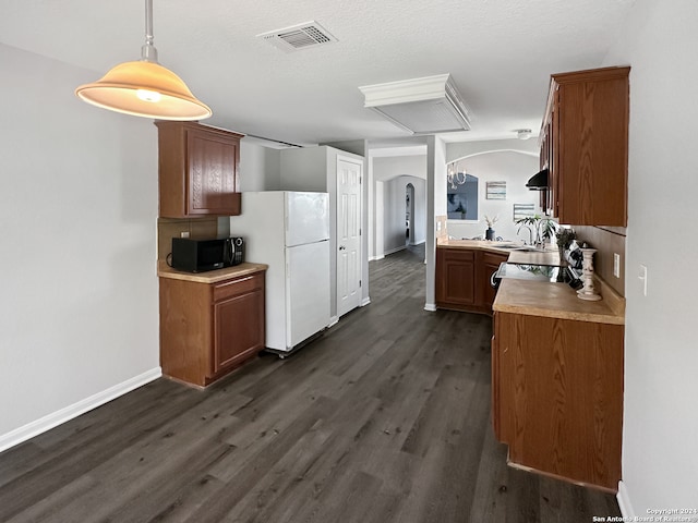 kitchen featuring dark hardwood / wood-style flooring, white fridge, hanging light fixtures, and a textured ceiling