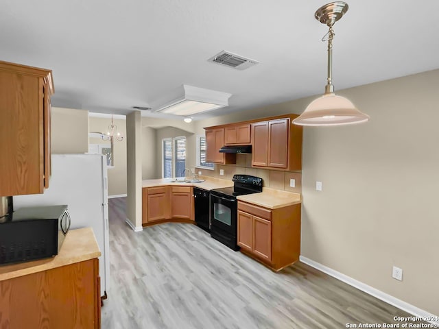 kitchen featuring pendant lighting, light hardwood / wood-style flooring, black appliances, and a notable chandelier