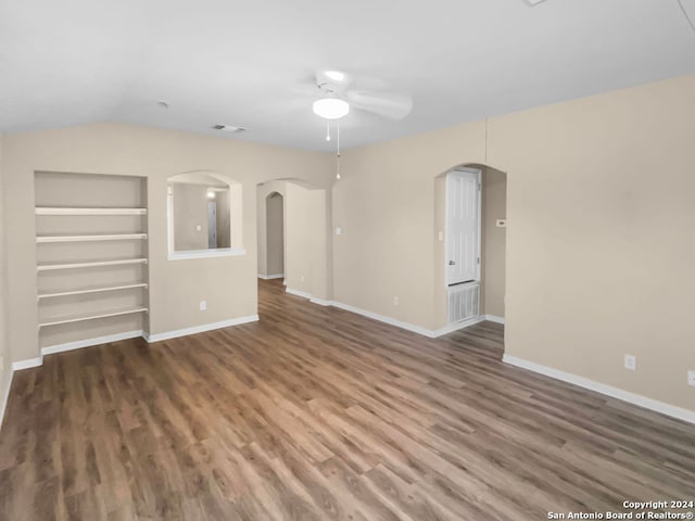 spare room featuring dark hardwood / wood-style floors, ceiling fan, vaulted ceiling, and built in shelves