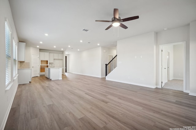 unfurnished living room with light hardwood / wood-style flooring, ceiling fan, and sink