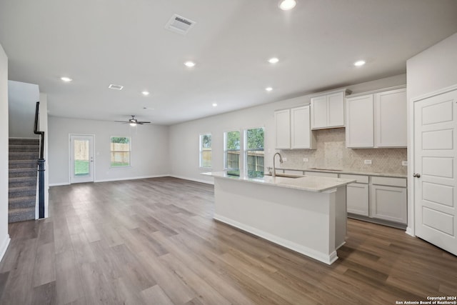 kitchen featuring ceiling fan, sink, hardwood / wood-style flooring, a center island with sink, and white cabinets