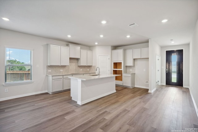 kitchen featuring white cabinets, a center island with sink, and sink