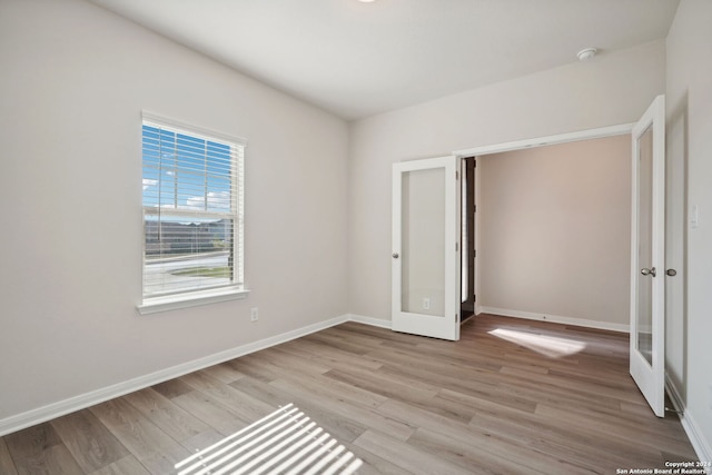 unfurnished bedroom with french doors and light wood-type flooring