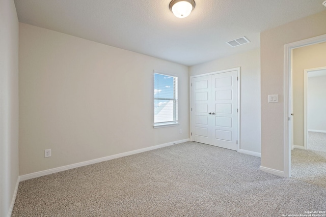 unfurnished bedroom featuring carpet, a textured ceiling, and a closet