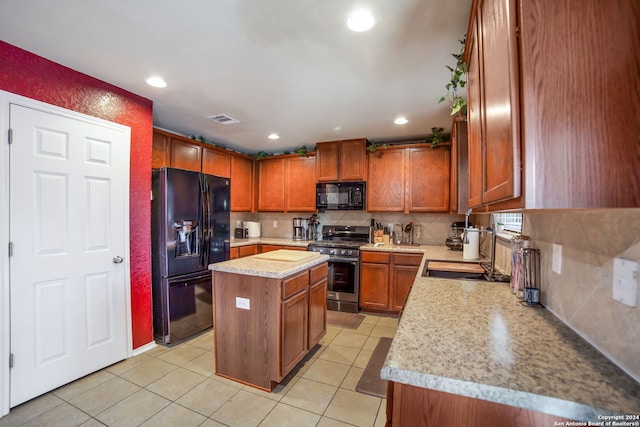 kitchen featuring light stone counters, light tile patterned floors, black appliances, and a kitchen island