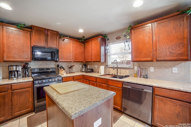 kitchen with stainless steel appliances, sink, a kitchen island, and light tile patterned floors