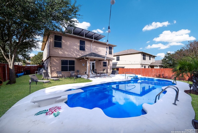 view of pool with a diving board, a lawn, and a patio