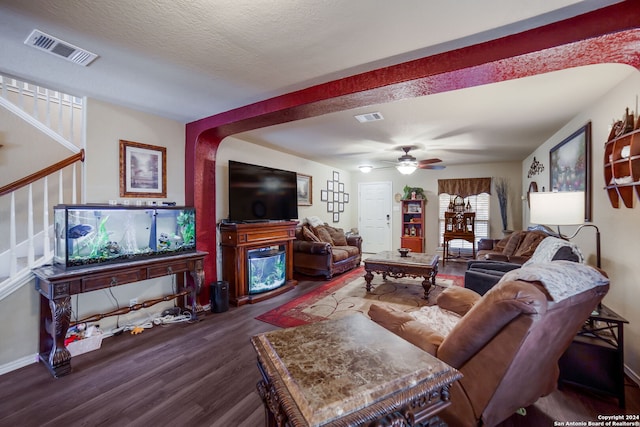 living room featuring a textured ceiling, dark wood-type flooring, and ceiling fan