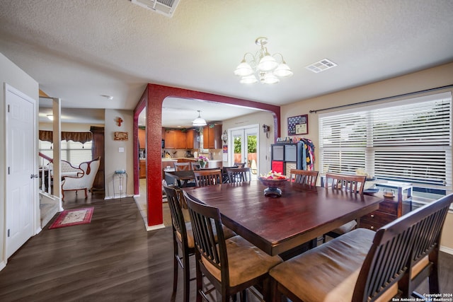 dining area featuring a textured ceiling, a notable chandelier, and dark hardwood / wood-style floors