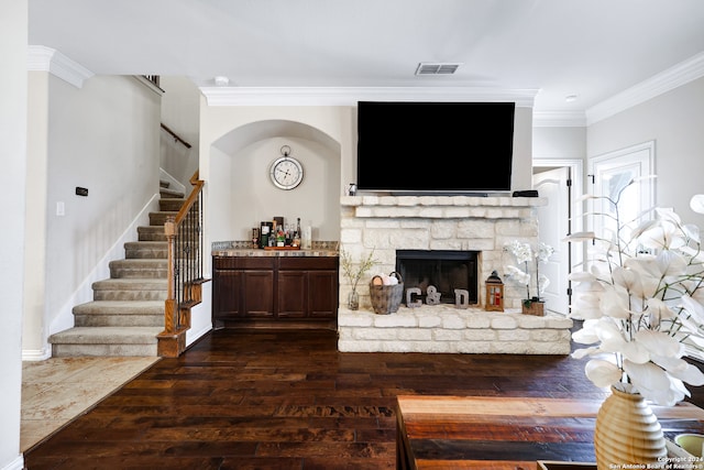 living room with dark wood-type flooring, a stone fireplace, and crown molding