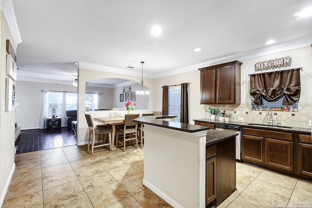 kitchen with sink, backsplash, crown molding, a center island, and dishwasher