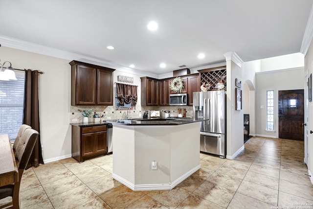 kitchen with crown molding, appliances with stainless steel finishes, dark brown cabinetry, decorative backsplash, and a center island