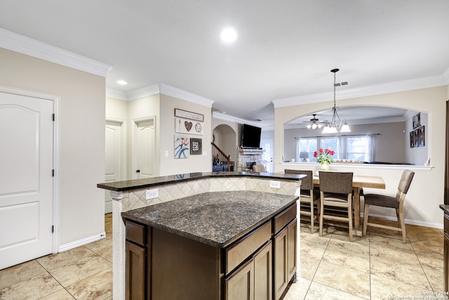 kitchen with crown molding, decorative light fixtures, dark brown cabinetry, dark stone countertops, and a chandelier