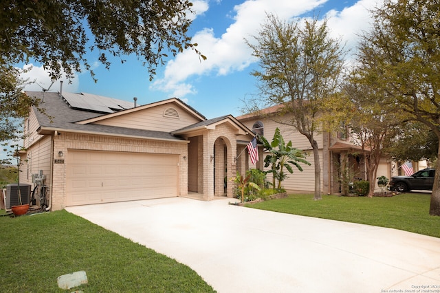 view of front of house featuring solar panels, a front lawn, central AC unit, and a garage