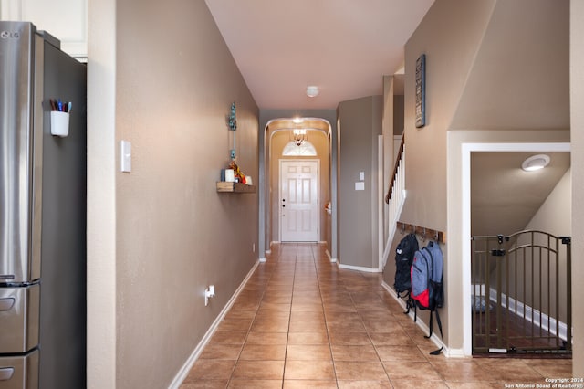 entryway with light tile patterned floors and a notable chandelier