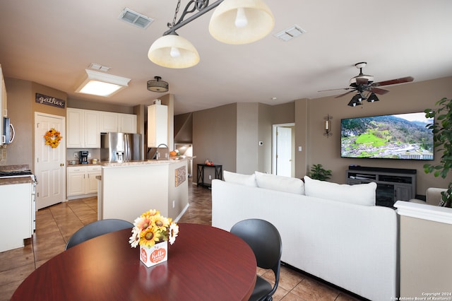 tiled dining area with ceiling fan and sink