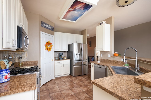 kitchen with kitchen peninsula, appliances with stainless steel finishes, white cabinetry, and sink