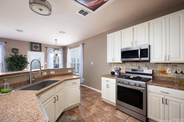 kitchen featuring white cabinetry, sink, decorative light fixtures, and appliances with stainless steel finishes