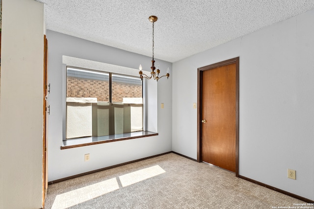 carpeted spare room with a chandelier and a textured ceiling