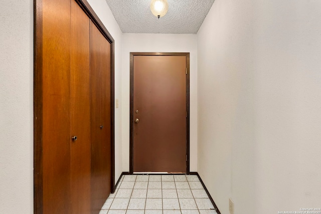 doorway featuring a textured ceiling and light tile patterned floors