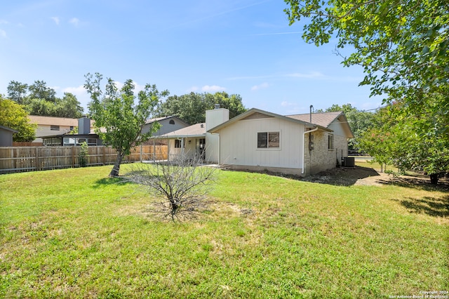 rear view of property with central AC and a yard