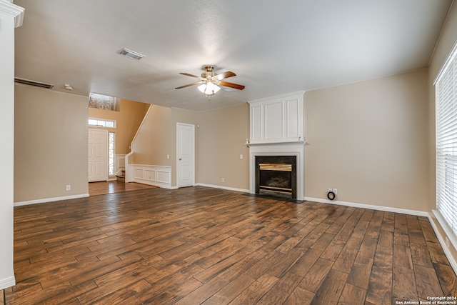 unfurnished living room with a large fireplace, dark hardwood / wood-style flooring, a healthy amount of sunlight, and ceiling fan