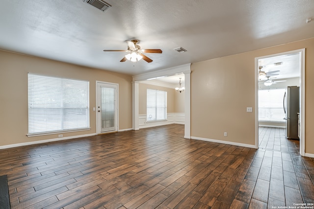 unfurnished living room featuring dark hardwood / wood-style flooring, a textured ceiling, ceiling fan with notable chandelier, and plenty of natural light