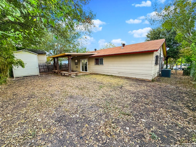 back of house featuring central AC unit, a patio area, and a shed