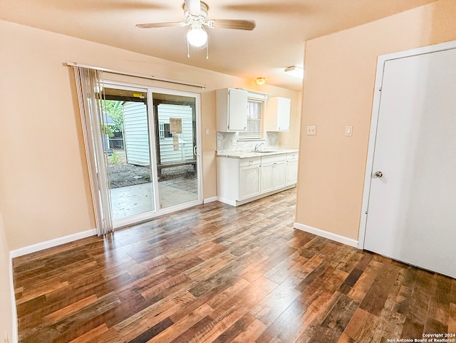 unfurnished living room featuring dark wood-type flooring, ceiling fan, and sink