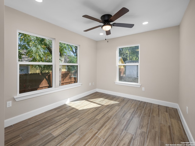 empty room with ceiling fan, wood-type flooring, and a healthy amount of sunlight