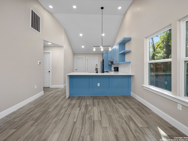 kitchen with kitchen peninsula, black / electric stove, high vaulted ceiling, light wood-type flooring, and decorative light fixtures