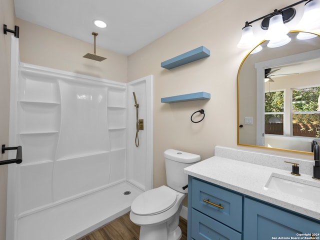 bathroom featuring walk in shower, ceiling fan, wood-type flooring, vanity, and toilet