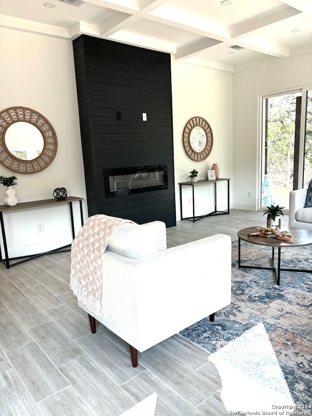 living room featuring coffered ceiling, hardwood / wood-style floors, a large fireplace, and beam ceiling