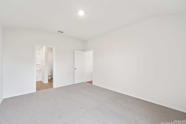 carpeted spare room featuring vaulted ceiling