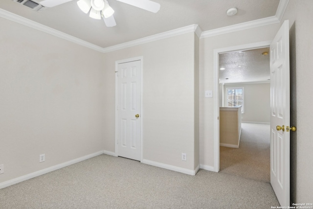 unfurnished bedroom with ceiling fan, a textured ceiling, crown molding, and light colored carpet