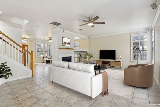 tiled living room featuring ornamental molding, a textured ceiling, and ceiling fan