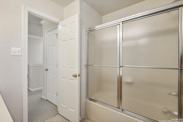 bathroom featuring bath / shower combo with glass door and tile patterned flooring